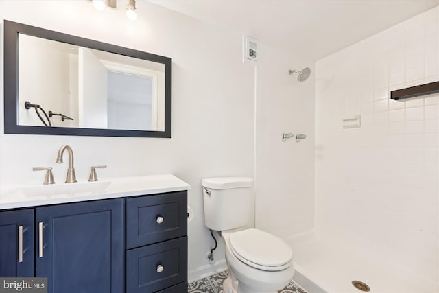 full bath with toilet, vanity, tiled shower, and baseboards