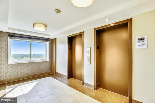 tiled spare room featuring elevator and baseboards