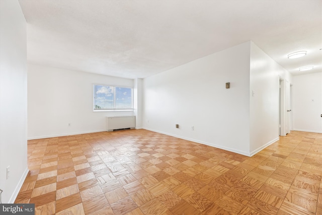 spare room with baseboards and radiator heating unit