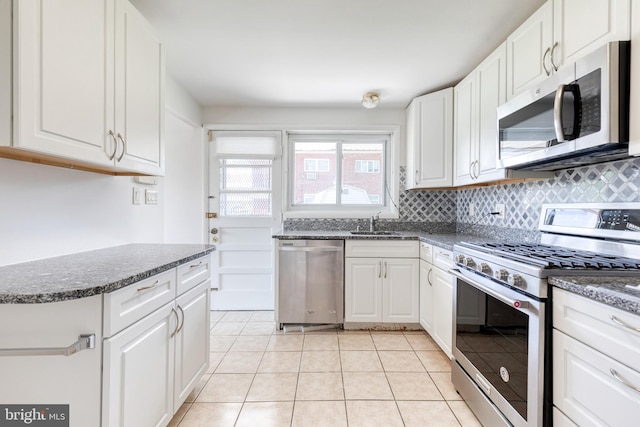 kitchen with appliances with stainless steel finishes, a sink, white cabinetry, and backsplash