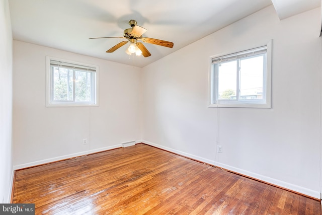 unfurnished room with wood-type flooring, a ceiling fan, and baseboards