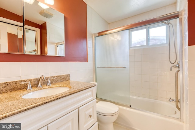 full bath featuring tile walls, vanity, shower / bath combination with glass door, and toilet