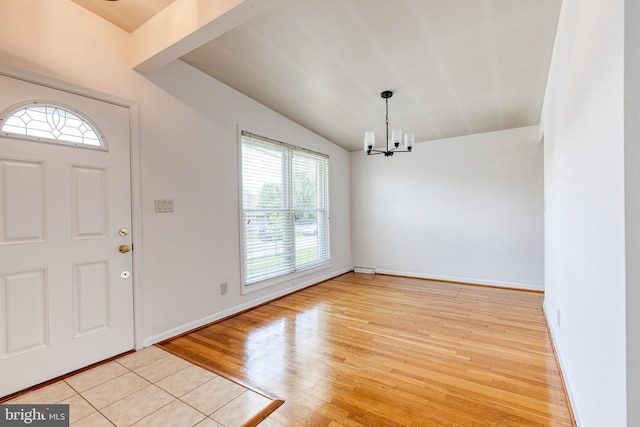 entrance foyer with vaulted ceiling, light wood-style flooring, a chandelier, and baseboards