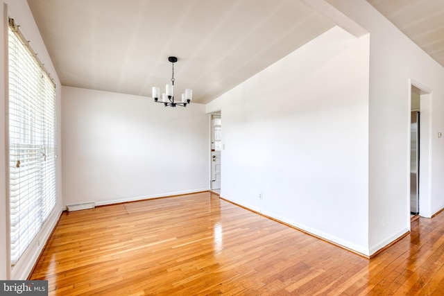 empty room with a chandelier, hardwood / wood-style flooring, and baseboards