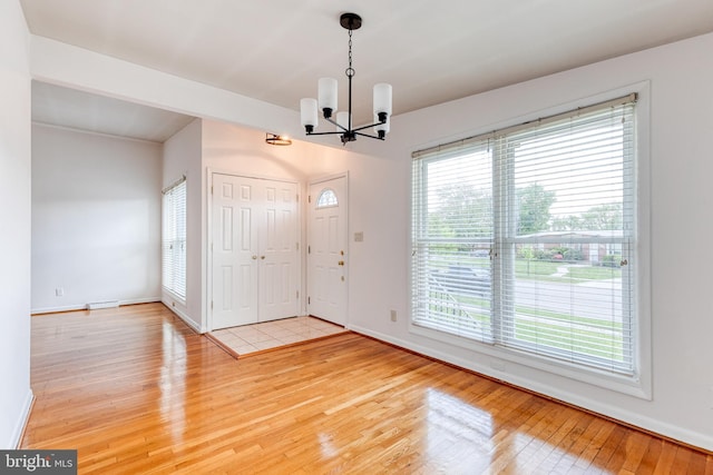 entryway featuring a chandelier, light wood finished floors, and baseboards