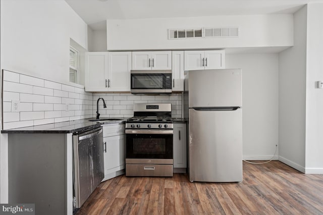 2214 N Cleveland St, Philadelphia, PA 19132 - kitchen featuring stainless steel appliances, a sink, dark countertops, white cabinetry, and decorative backsplash