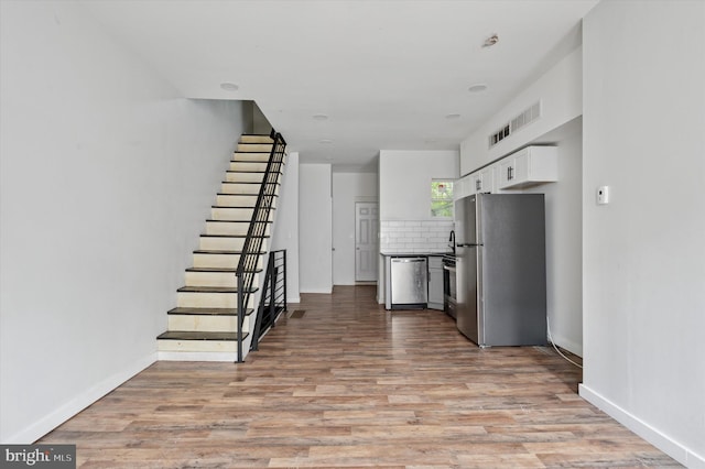 2214 N Cleveland St, Philadelphia, PA 19132 - kitchen featuring appliances with stainless steel finishes, tasteful backsplash, light wood-type flooring, white cabinetry, and baseboards