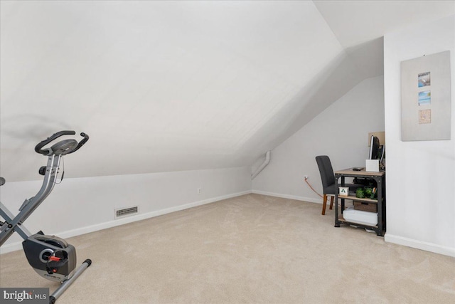 exercise area featuring light carpet, lofted ceiling, and baseboards