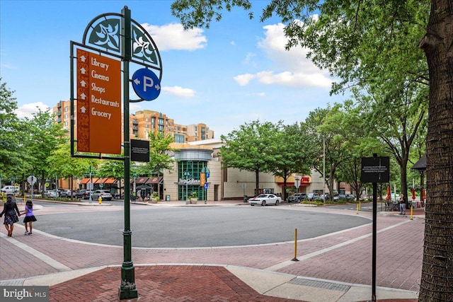 view of asphalt road with sidewalks, traffic signs, street lighting, and curbs