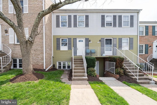 view of property featuring stairs and brick siding