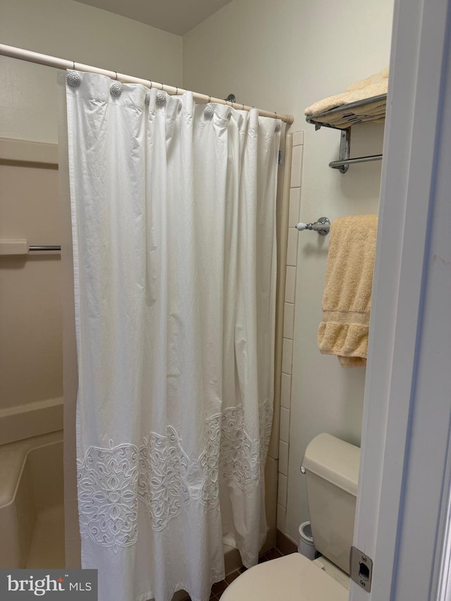 bathroom featuring toilet and curtained shower