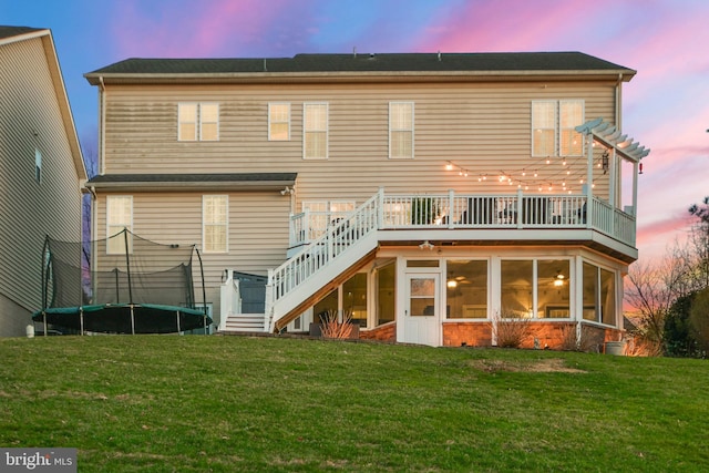 4108 Brushfield Dr, Frederick, MD 21704 - back of property at dusk featuring a trampoline, stairway, a sunroom, and a yard