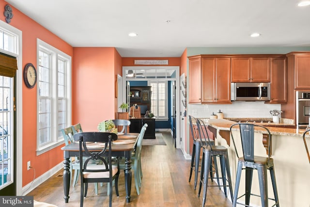 4108 Brushfield Dr, Frederick, MD 21704 - kitchen featuring appliances with stainless steel finishes, a kitchen breakfast bar, light wood-style floors, tasteful backsplash, and baseboards