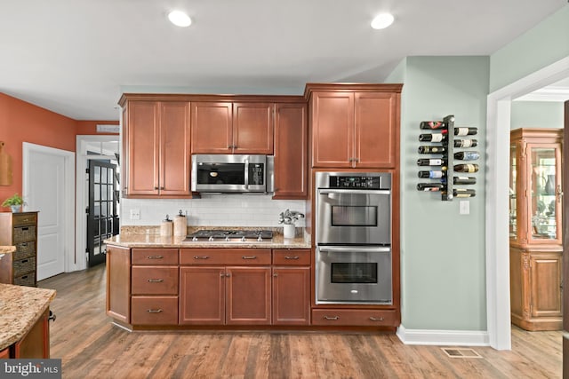 4108 Brushfield Dr, Frederick, MD 21704 - kitchen with appliances with stainless steel finishes, light stone countertops, decorative backsplash, light wood finished floors, and baseboards