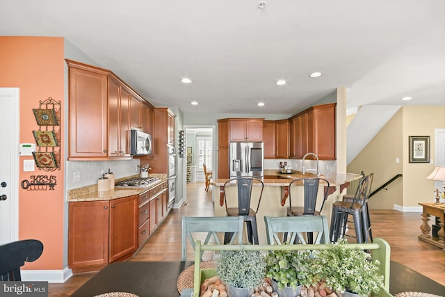 4108 Brushfield Dr, Frederick, MD 21704 - kitchen featuring appliances with stainless steel finishes, a peninsula, light stone countertops, decorative backsplash, and wood finished floors
