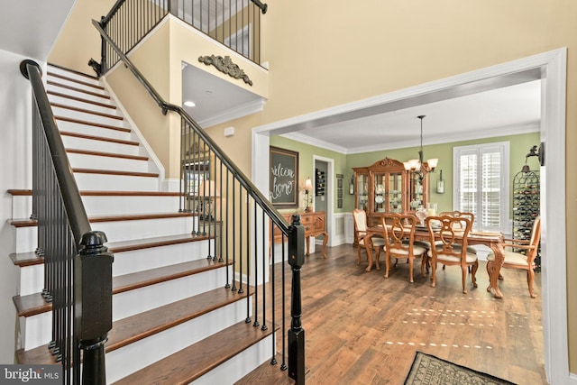 4108 Brushfield Dr, Frederick, MD 21704 - stairs featuring ornamental molding, wood finished floors, a chandelier, and a wainscoted wall