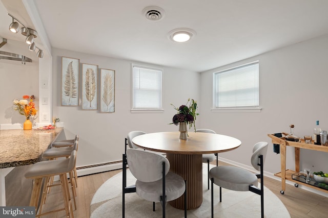 dining room with a baseboard radiator, light wood finished floors, and baseboards