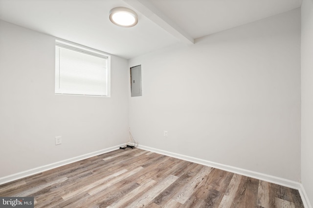 unfurnished room featuring electric panel, wood finished floors, and baseboards