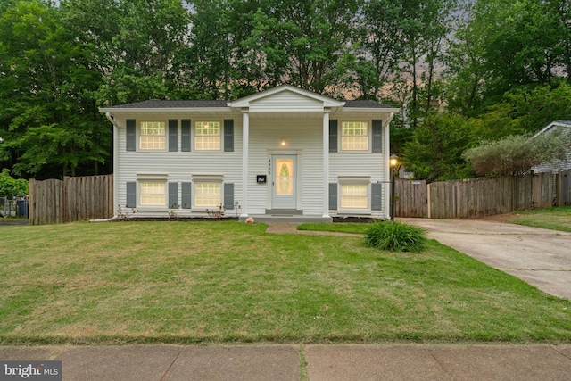 split foyer home with driveway and view of scattered trees