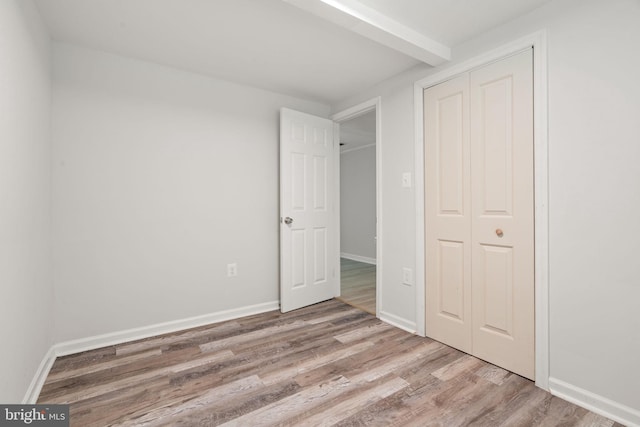 unfurnished bedroom featuring wood finished floors, a closet, and baseboards