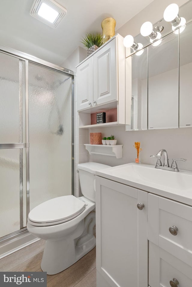 full bath with toilet, a shower stall, vanity, and wood finished floors