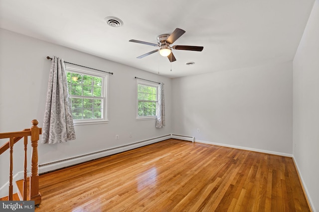 spare room with baseboard heating, light wood-style floors, baseboards, and ceiling fan