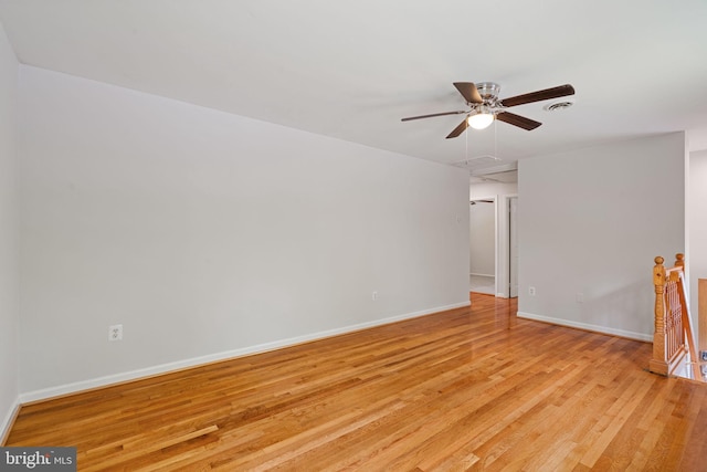 spare room featuring light wood-style flooring, a ceiling fan, and baseboards