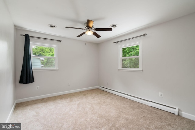 empty room featuring a baseboard heating unit, healthy amount of natural light, a ceiling fan, and carpet floors