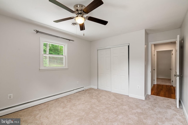 unfurnished bedroom featuring a baseboard heating unit, carpet, a closet, baseboards, and ceiling fan