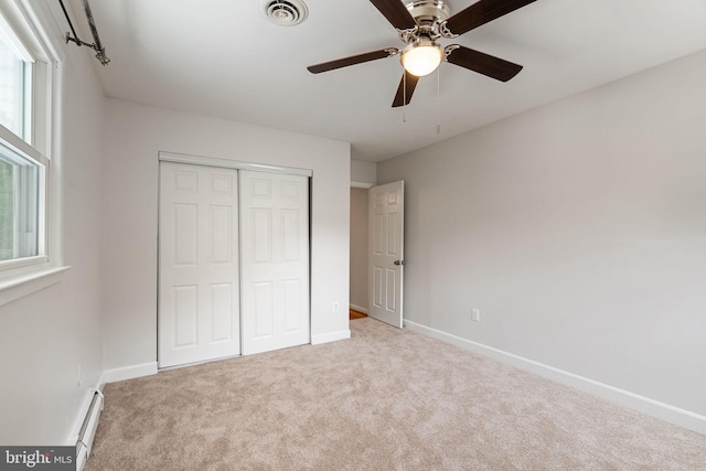 unfurnished bedroom featuring a baseboard radiator, carpet flooring, a closet, baseboards, and ceiling fan