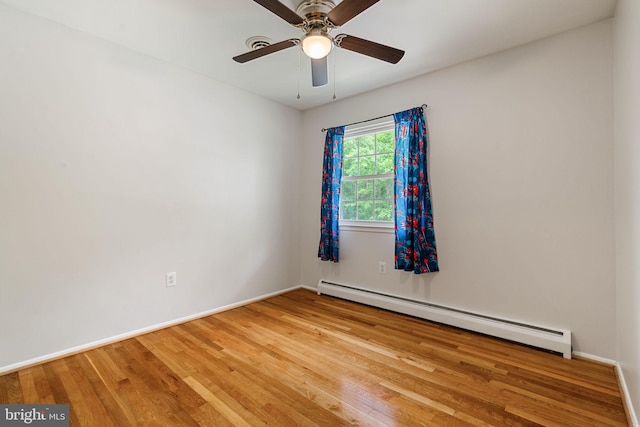 empty room with baseboard heating, wood finished floors, a ceiling fan, and baseboards