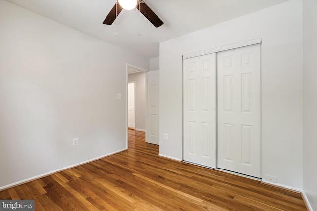 unfurnished bedroom with wood finished floors, baseboards, a closet, and ceiling fan