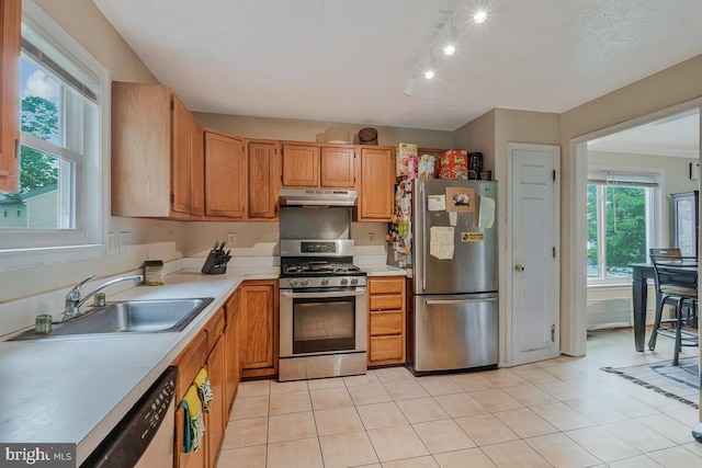 kitchen featuring stainless steel appliances, a sink, under cabinet range hood, light countertops, and light tile patterned flooring