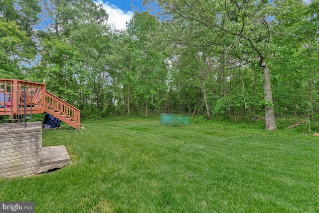 view of green lawn with stairway and a deck