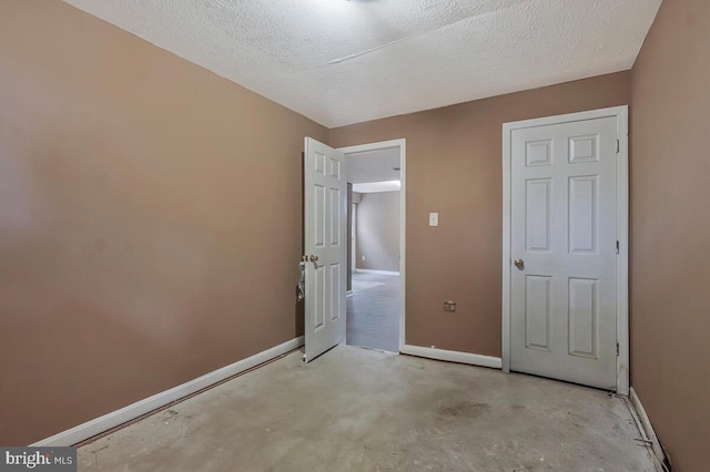 unfurnished bedroom featuring baseboards, concrete flooring, and a textured ceiling