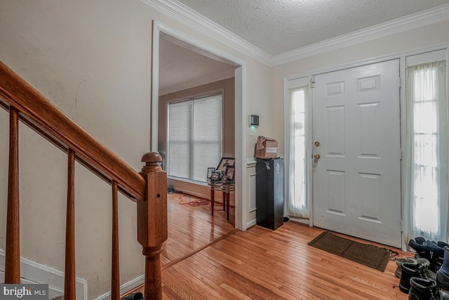 entrance foyer with light wood finished floors, crown molding, plenty of natural light, and a textured ceiling