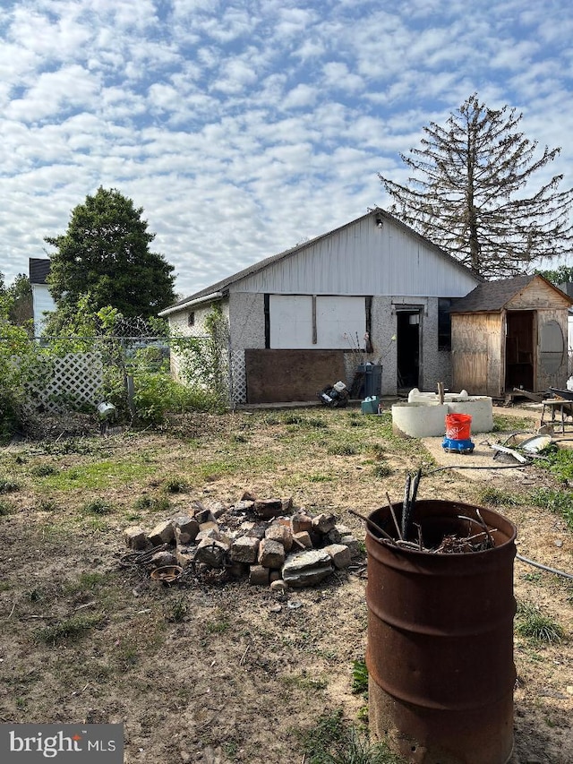 back of house with fence, a storage shed, and an outbuilding