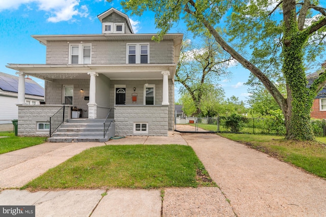 traditional style home with covered porch, a gate, concrete driveway, and stone siding