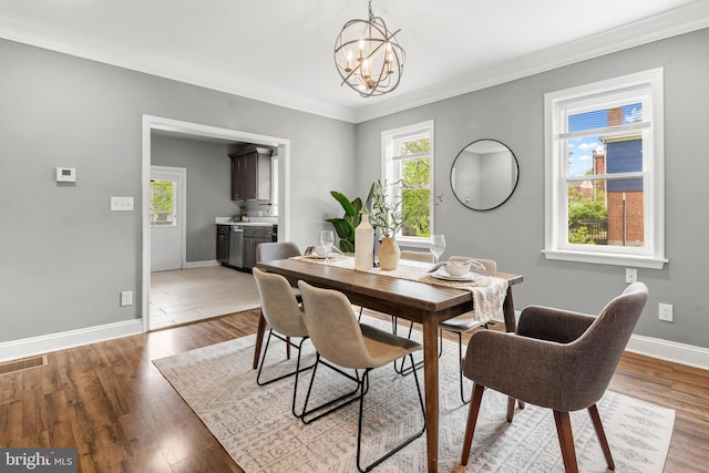 dining room featuring baseboards, a chandelier, ornamental molding, and light wood finished floors
