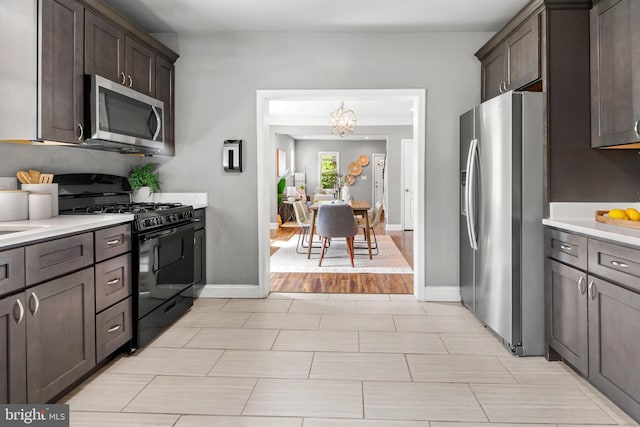 kitchen featuring appliances with stainless steel finishes, dark brown cabinets, light countertops, and a chandelier