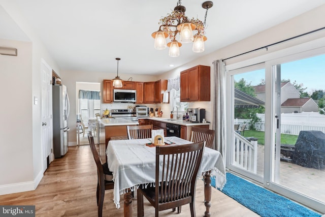 dining area with healthy amount of natural light, light wood finished floors, a chandelier, and baseboards