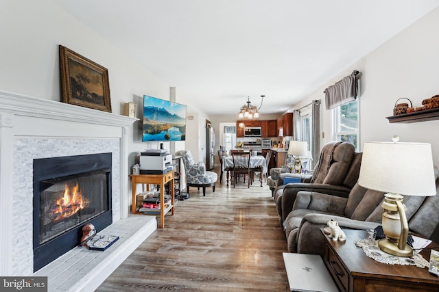 living area with wood finished floors, a lit fireplace, and a chandelier