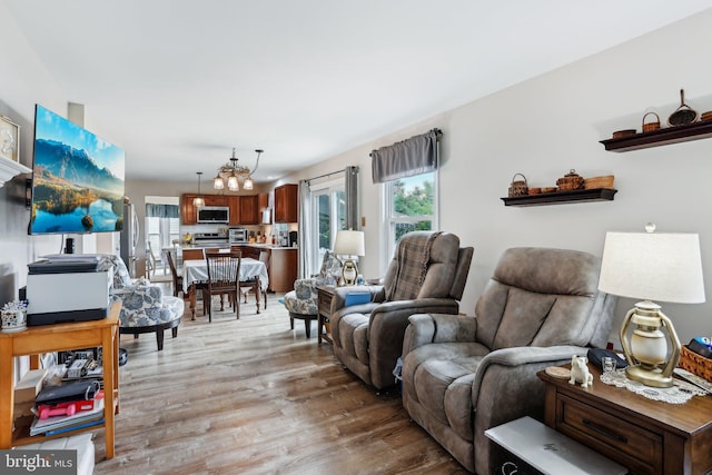 living room featuring light wood-style flooring, healthy amount of natural light, and a chandelier