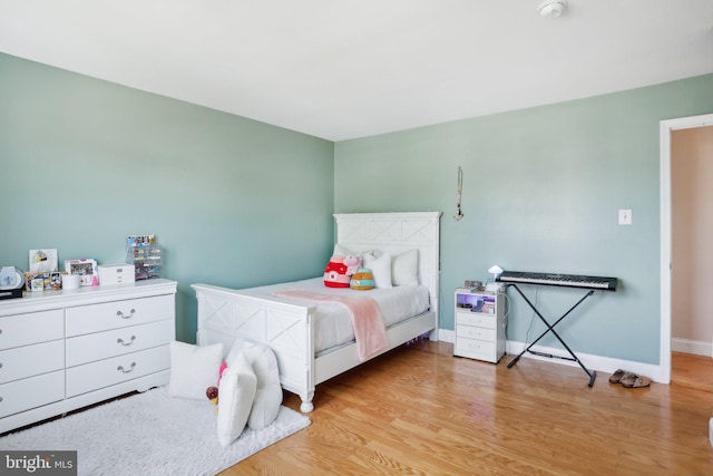 bedroom featuring light wood finished floors and baseboards