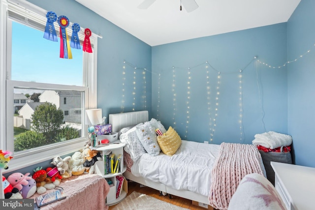bedroom featuring multiple windows, wood finished floors, and a ceiling fan