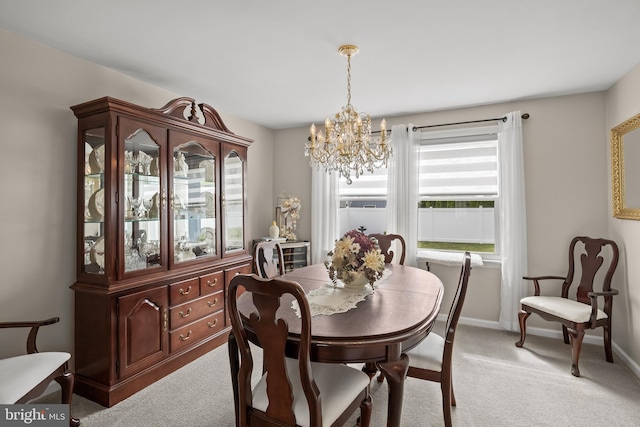 dining room featuring a chandelier, light carpet, and baseboards