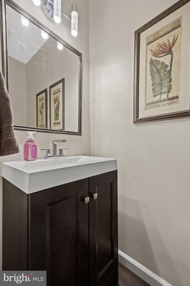 bathroom featuring vanity, wood finished floors, and baseboards