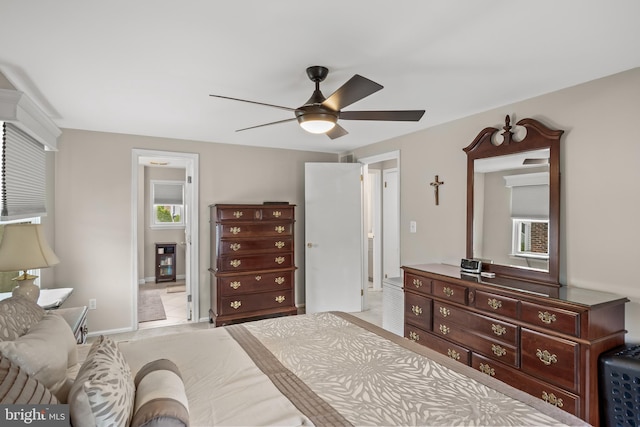 bedroom featuring connected bathroom, baseboards, and a ceiling fan