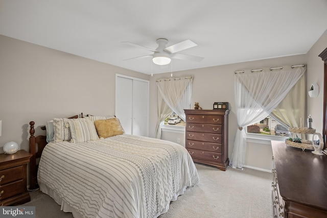 bedroom with light colored carpet, a closet, baseboards, and ceiling fan