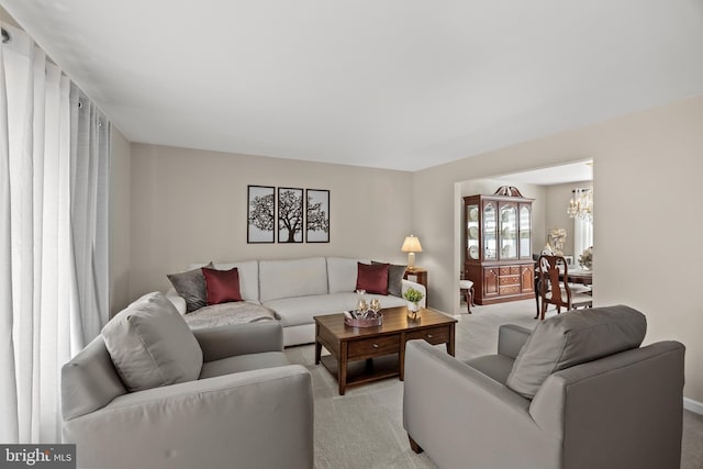 living area featuring light carpet, a chandelier, and baseboards